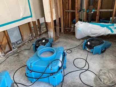Air movers and a dehumidifier drying opened walls and a slab floor in El Monte