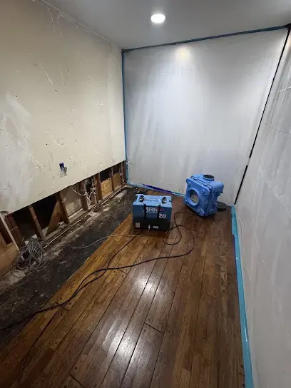 Containment walls and a dehumidifier drying hardwood and lower walls in El Monte
